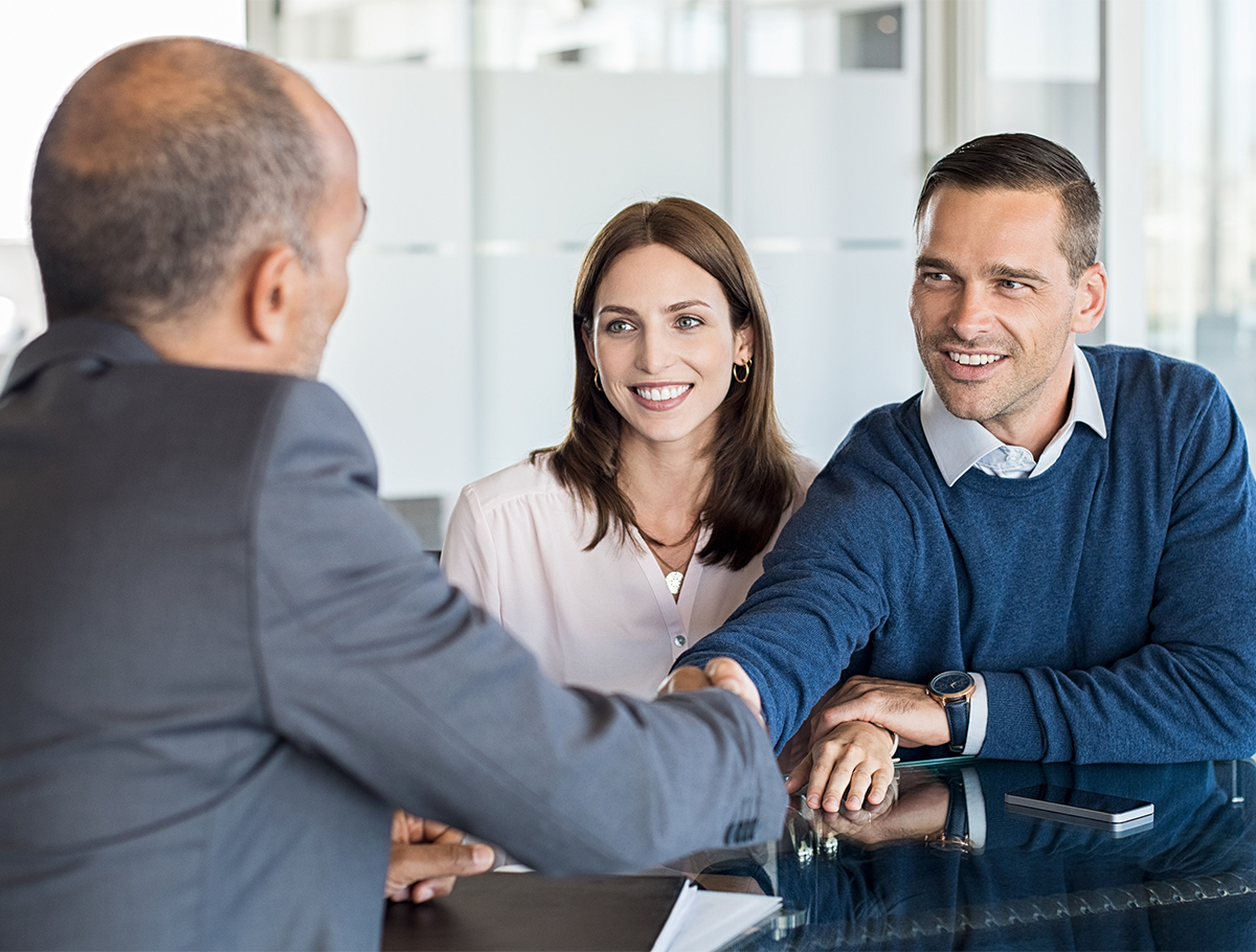 Couple shaking hands with advisor at desk