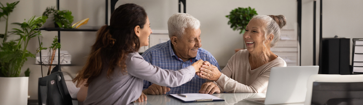 Senior Couple shaking hands with advisor in office