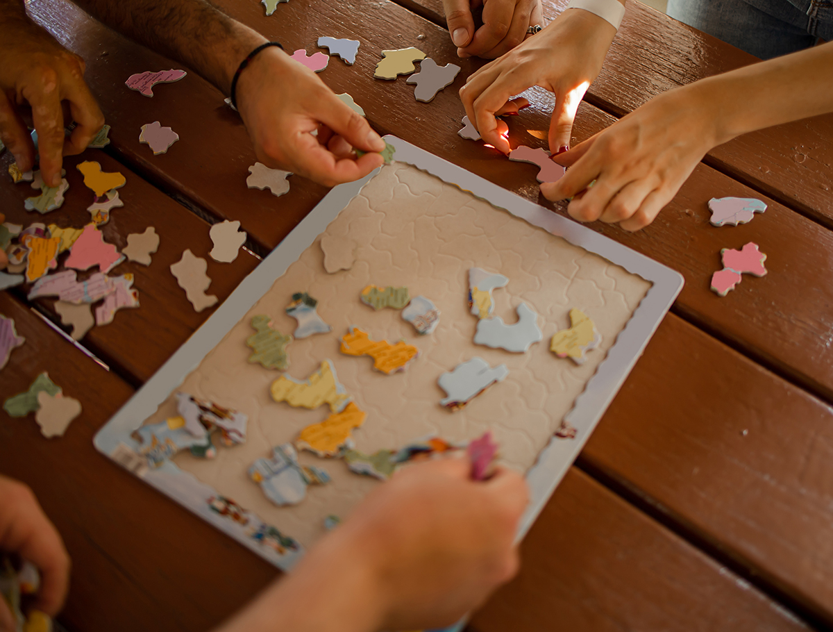 Close up of several hands working on puzzle